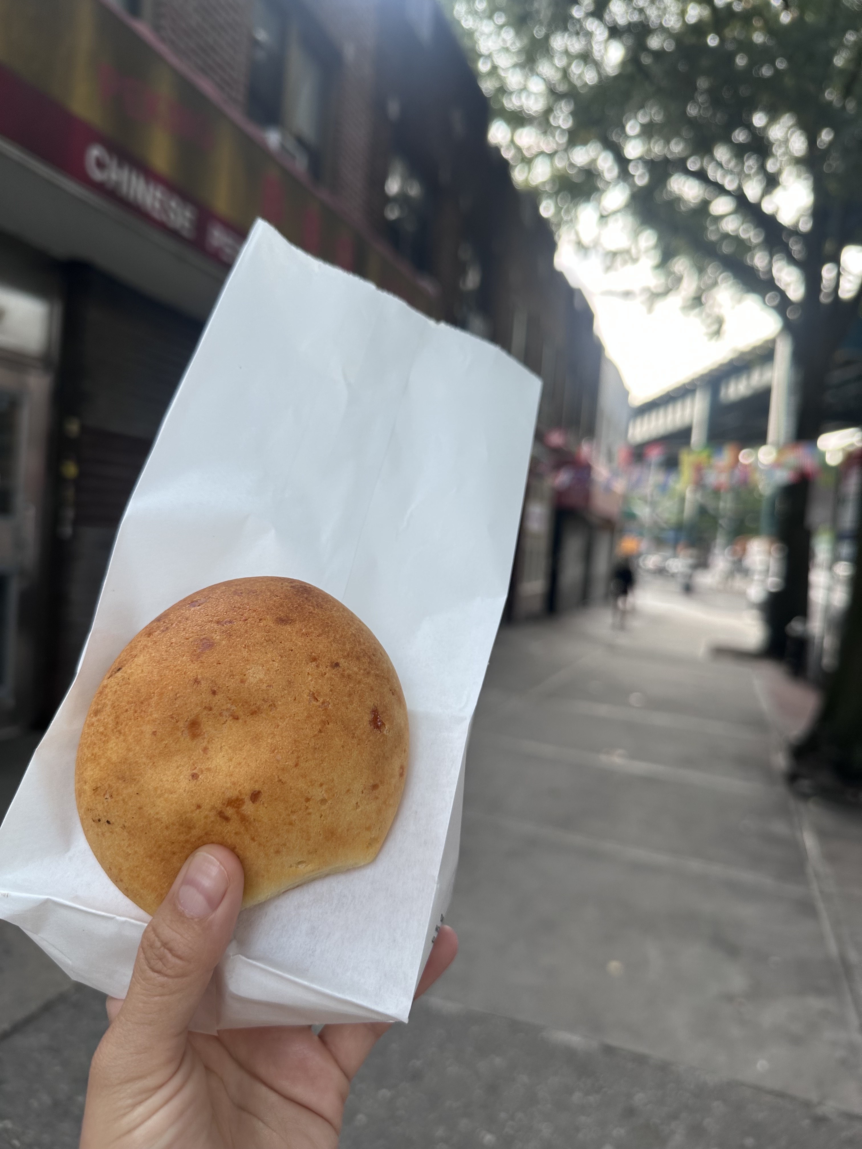 Pan de bono held in hand outside Rico Pan Bakery in Woodside Queens