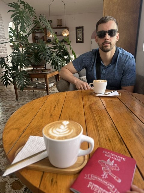 Latte and the red coffee passport on a round wooden table at Café Carmín in Cholula